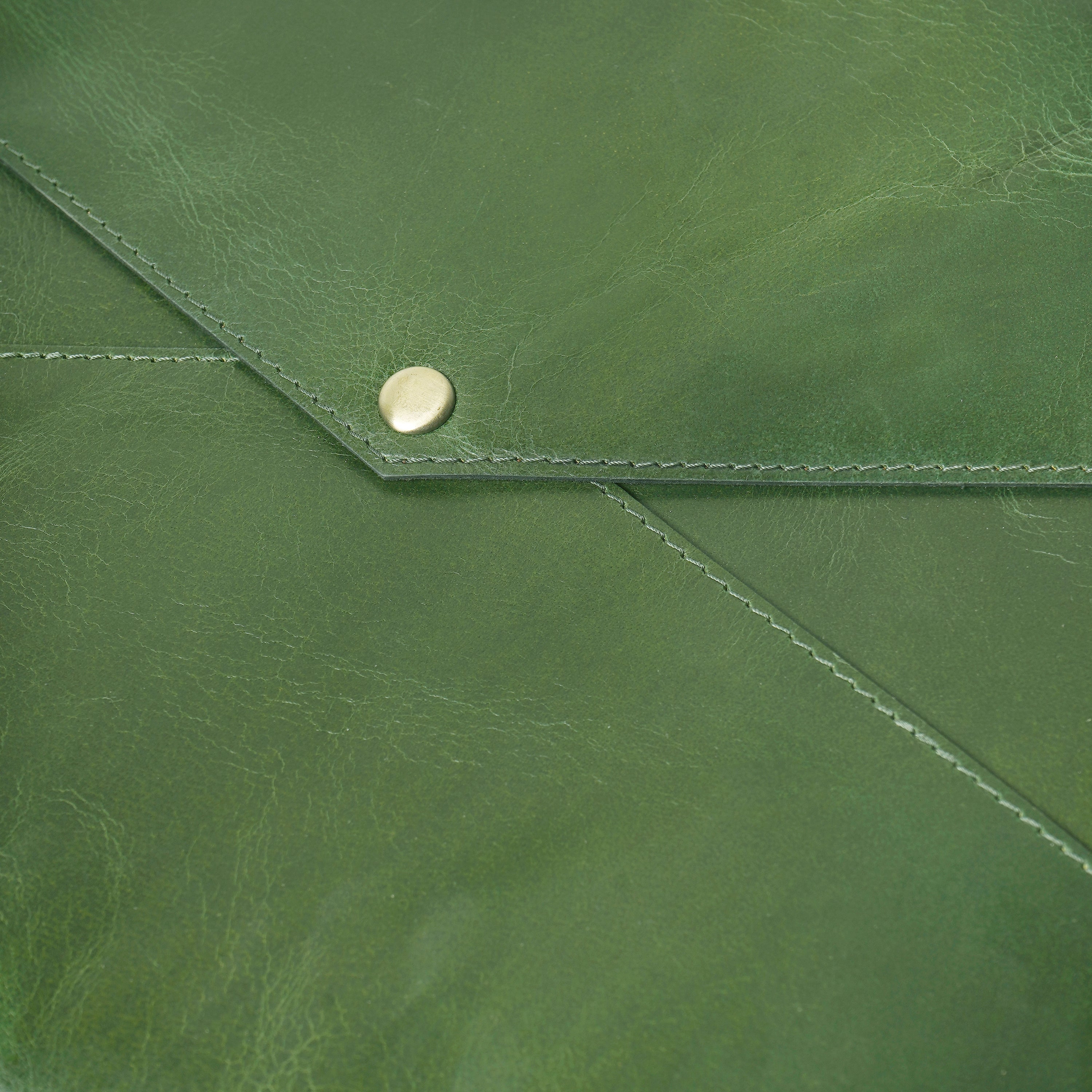 Close-up of a green leather envelope with a gold button.