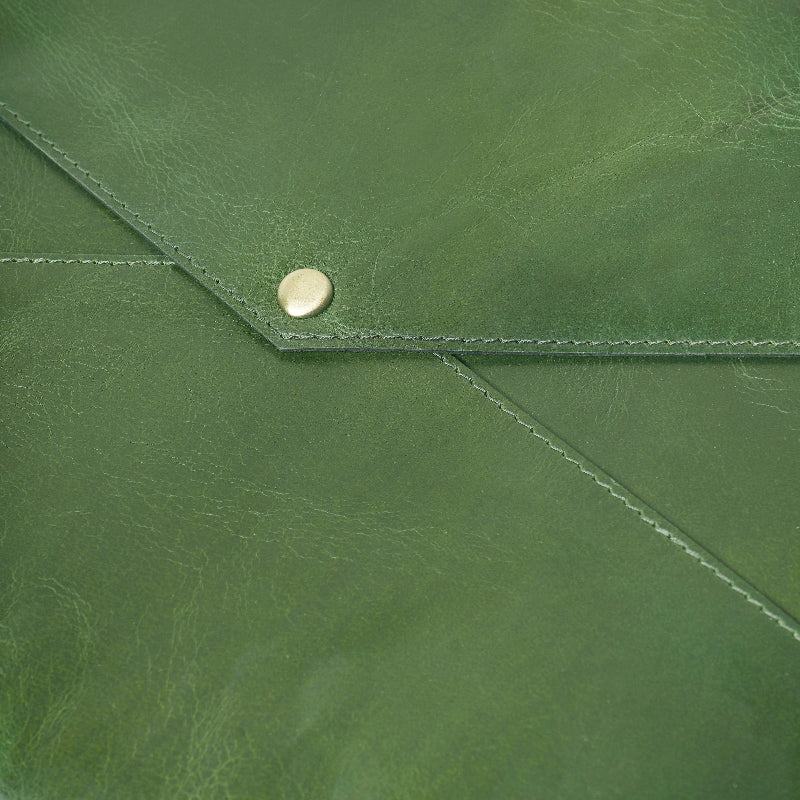 Close-up of a green leather sleeve with a gold button.
