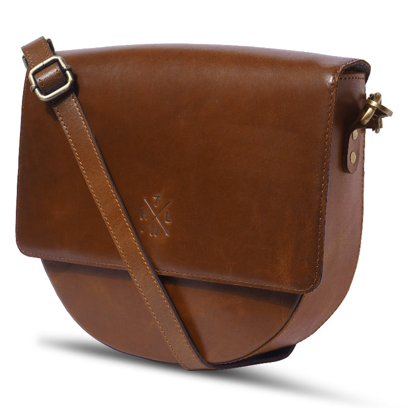 Brown leather saddle bag with a strap on a white background
