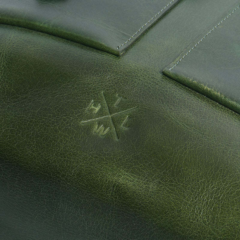 Close-up of a green leather surface with a subtle logo.
