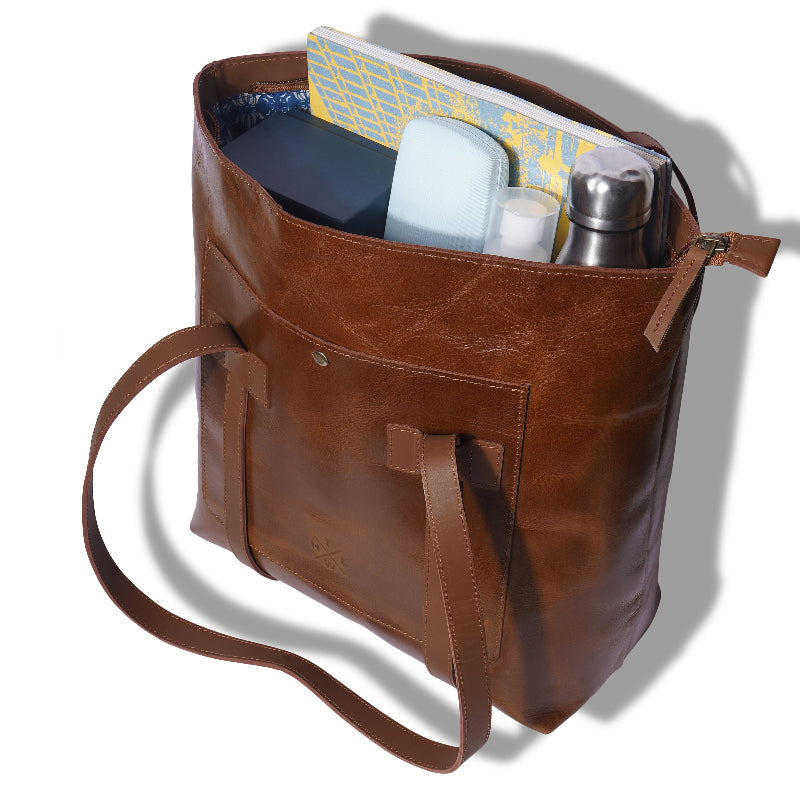 Brown leather tote bag with items inside on a white background