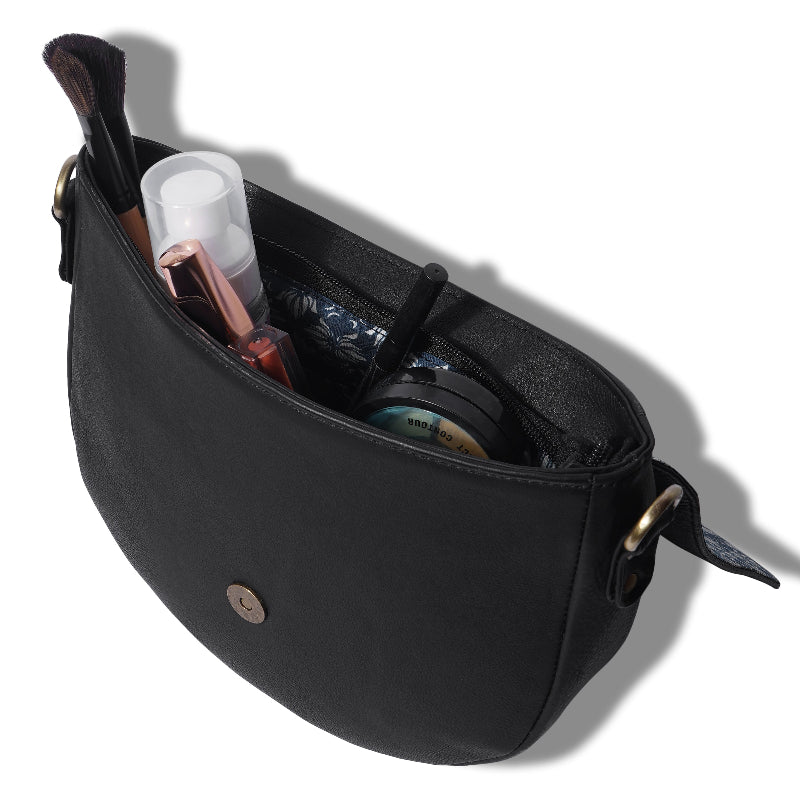 Black crossbody bag with various items inside on a white background