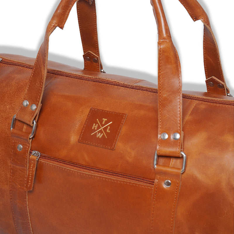 Brown leather duffel bag with visible brand logo on a white background