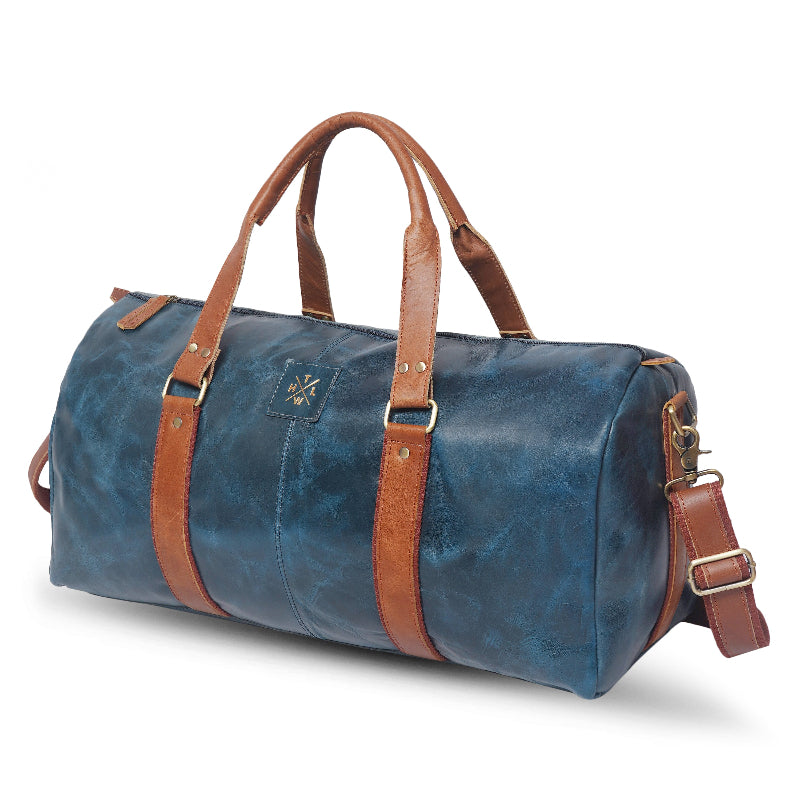Blue duffel bag with brown leather straps on a white background
