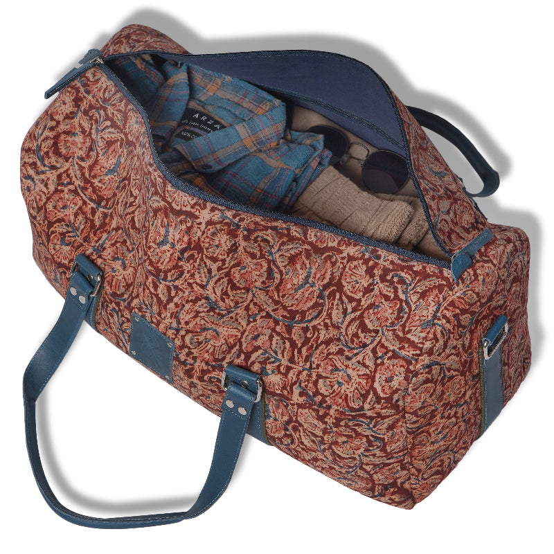 Patterned duffel bag with clothes partially inside on a white background