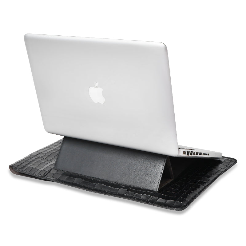 A white laptop on a black crocodile-patterned laptopsleeve a white background