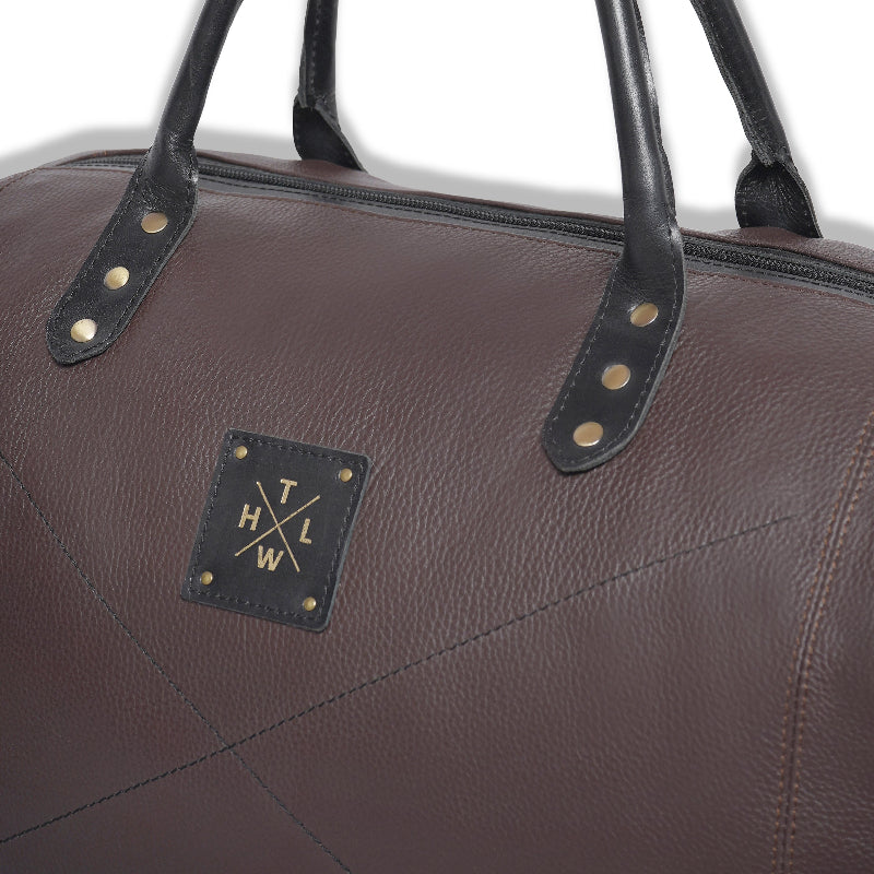 Brown leather bag with black straps and a logo on a white background