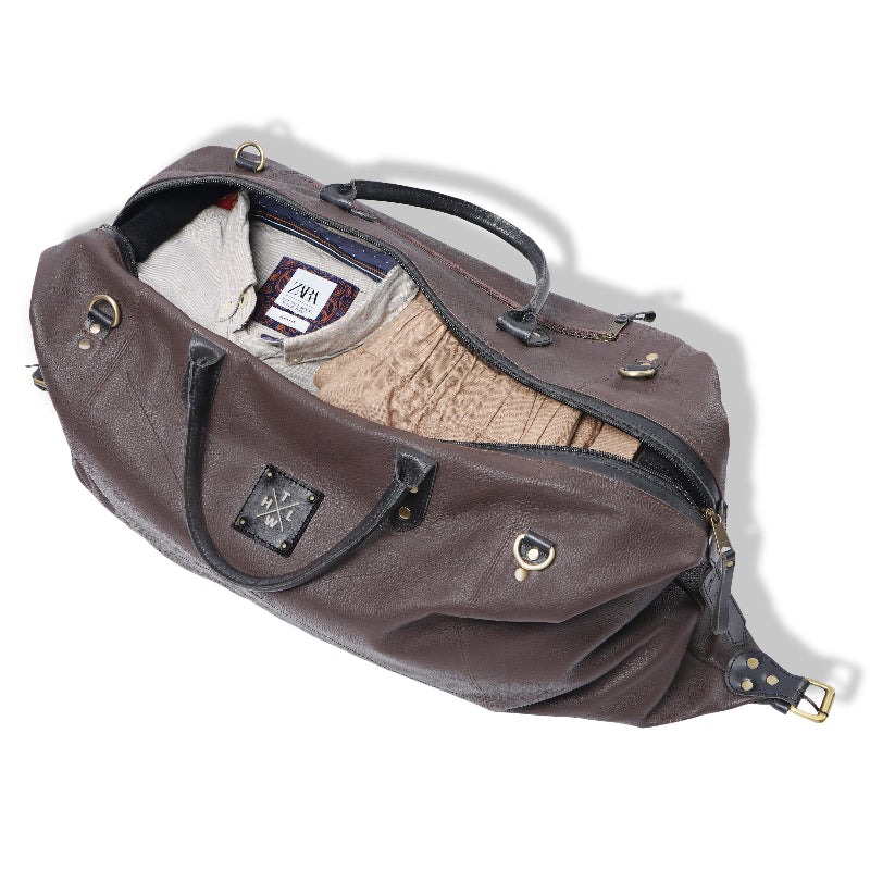 Brown duffel bag with clothing items on a white background