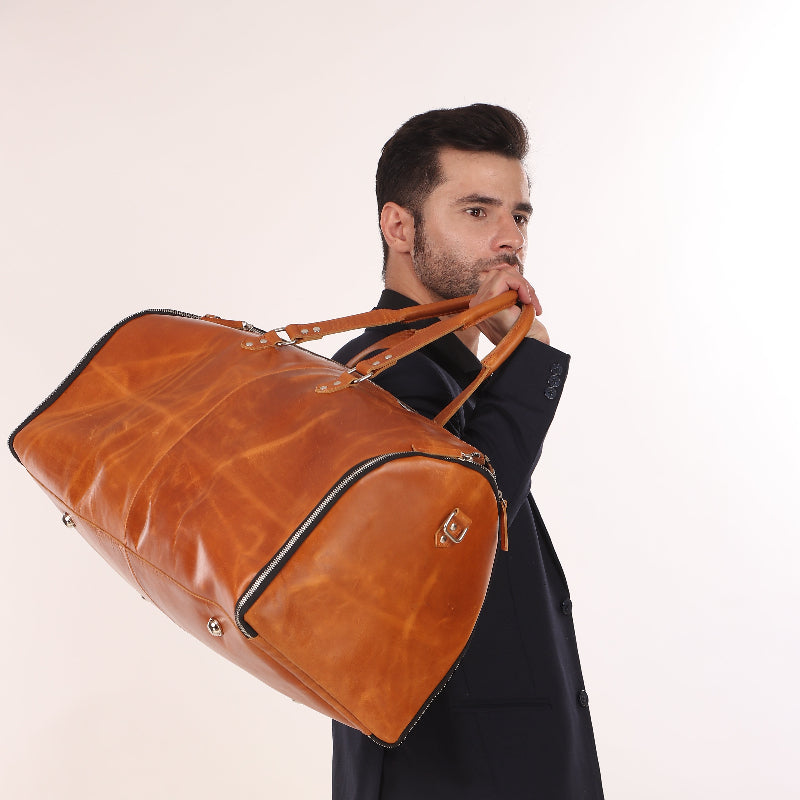 Man holding a large brown leather bag against a white background