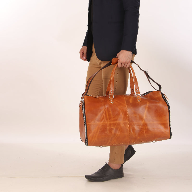 Man holding a brown leather bag against a plain background