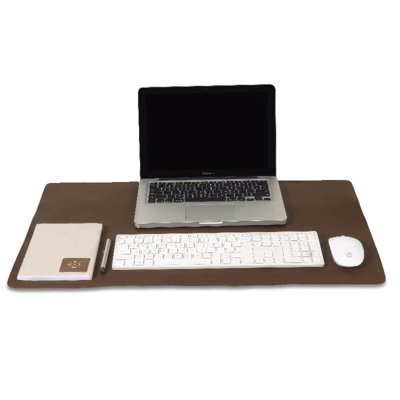 Laptop, keyboard, mouse, and notepad on a brown desk pad with a white background