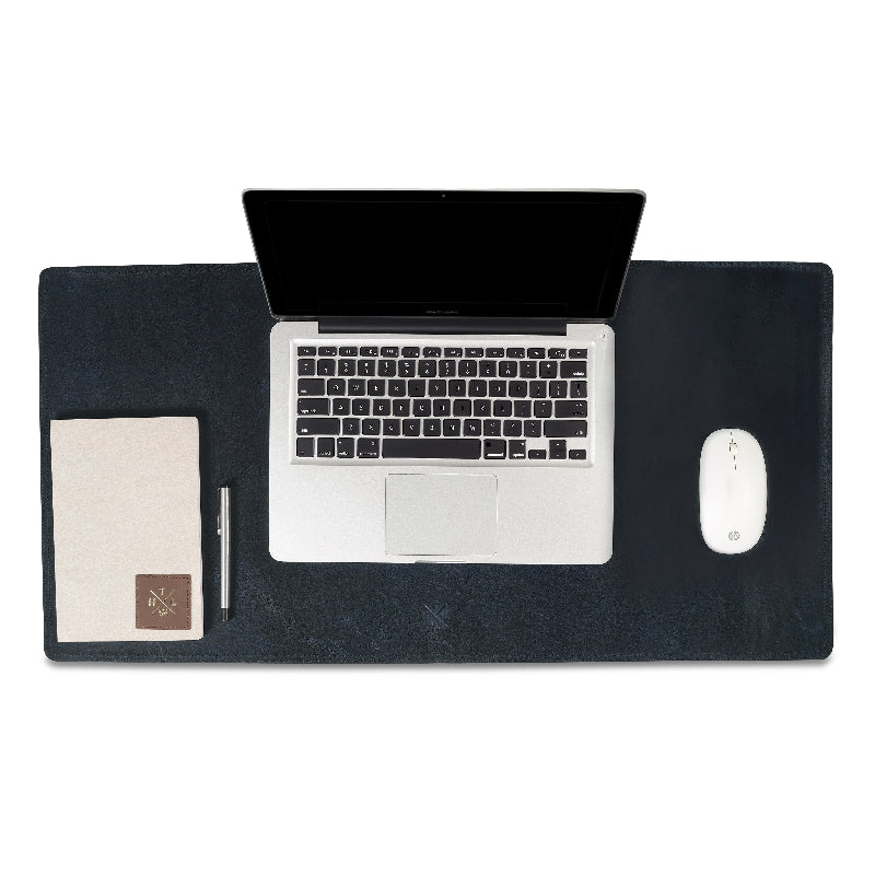 Laptop on a large black desk pad with a mouse and notebook on a white background