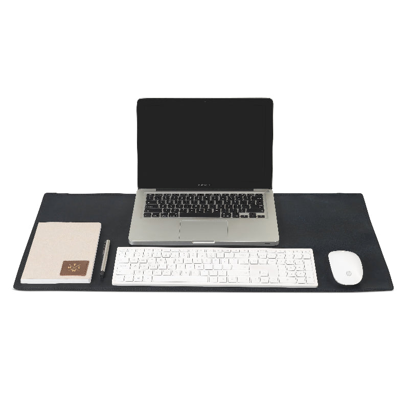Black desk mat with laptop, keyboard, mouse, and stationery on a white background