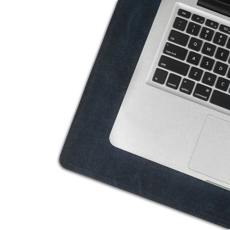 Laptop on a dark leather desk pad with a white background