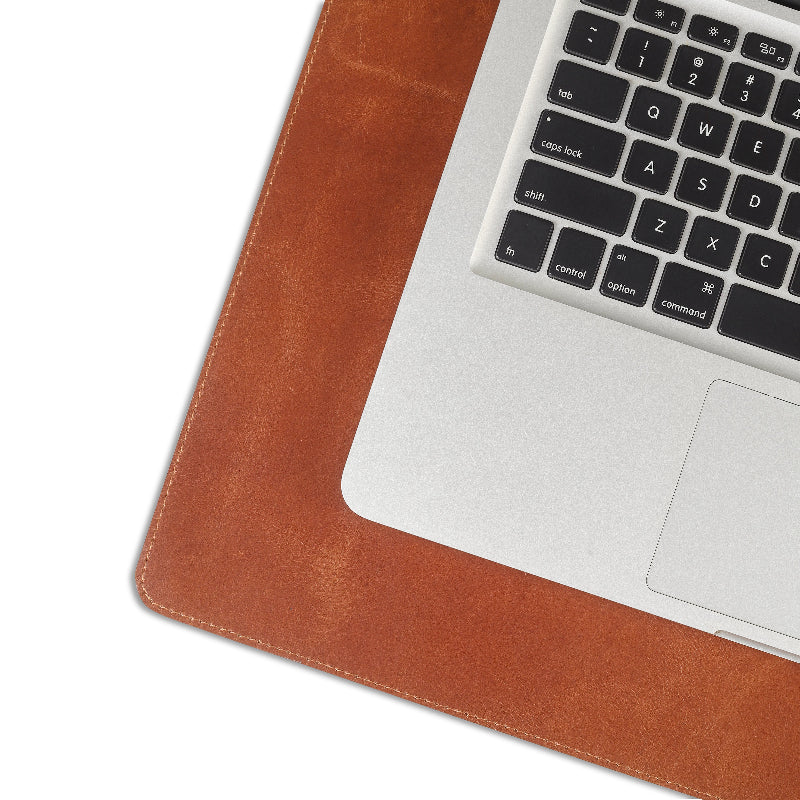 Laptop on a brown leather desk pad with a white background