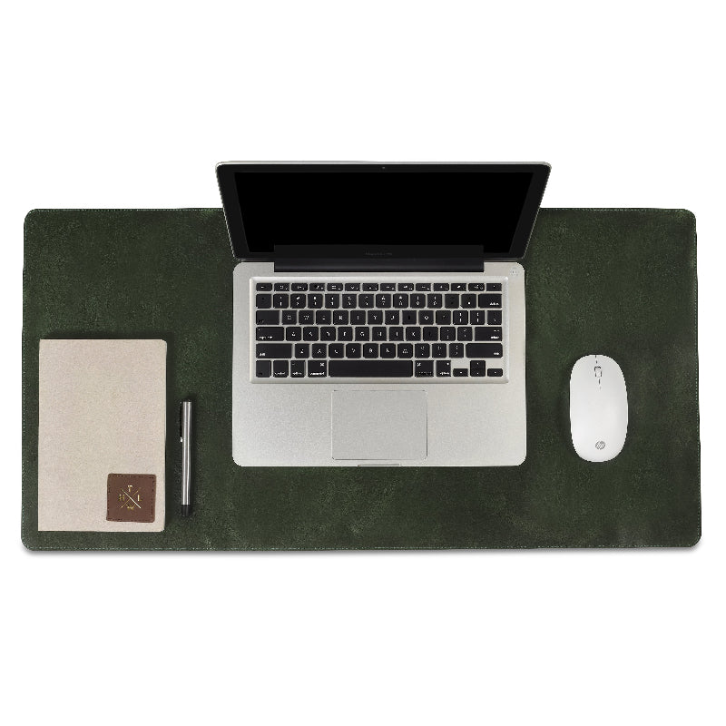 Laptop, mouse, and notebook on a dark green desk pad with a white background