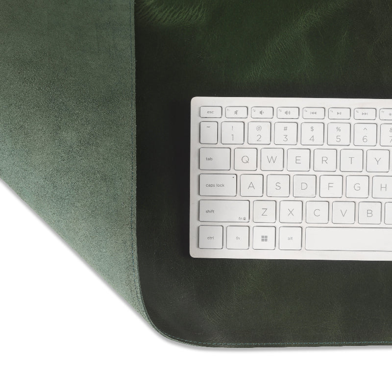 Green leather desk pad with a silver keyboard on a white background