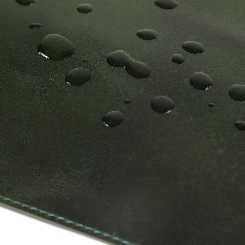 Close-up of water droplets on a green leather deask mat surface