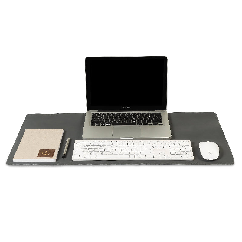Laptop, keyboard, mouse, and notebook on a large desk pad with a white background
