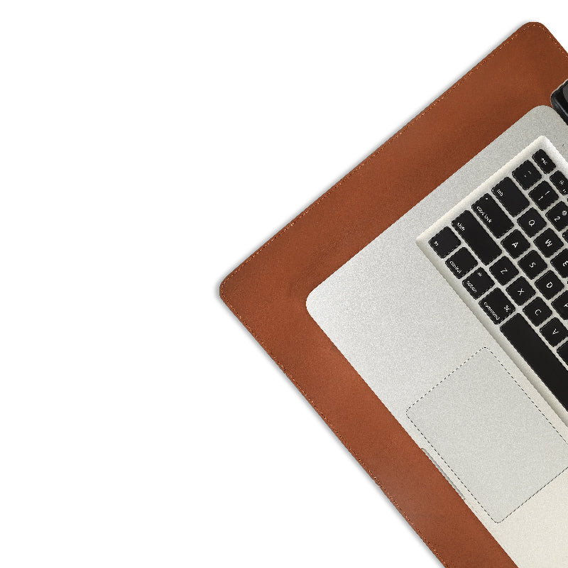 Laptop on a brown leather desk pad with a white background