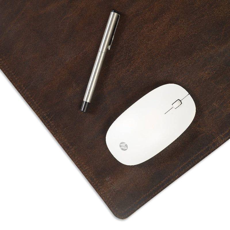 White mouse and pen on a brown leather desk pad