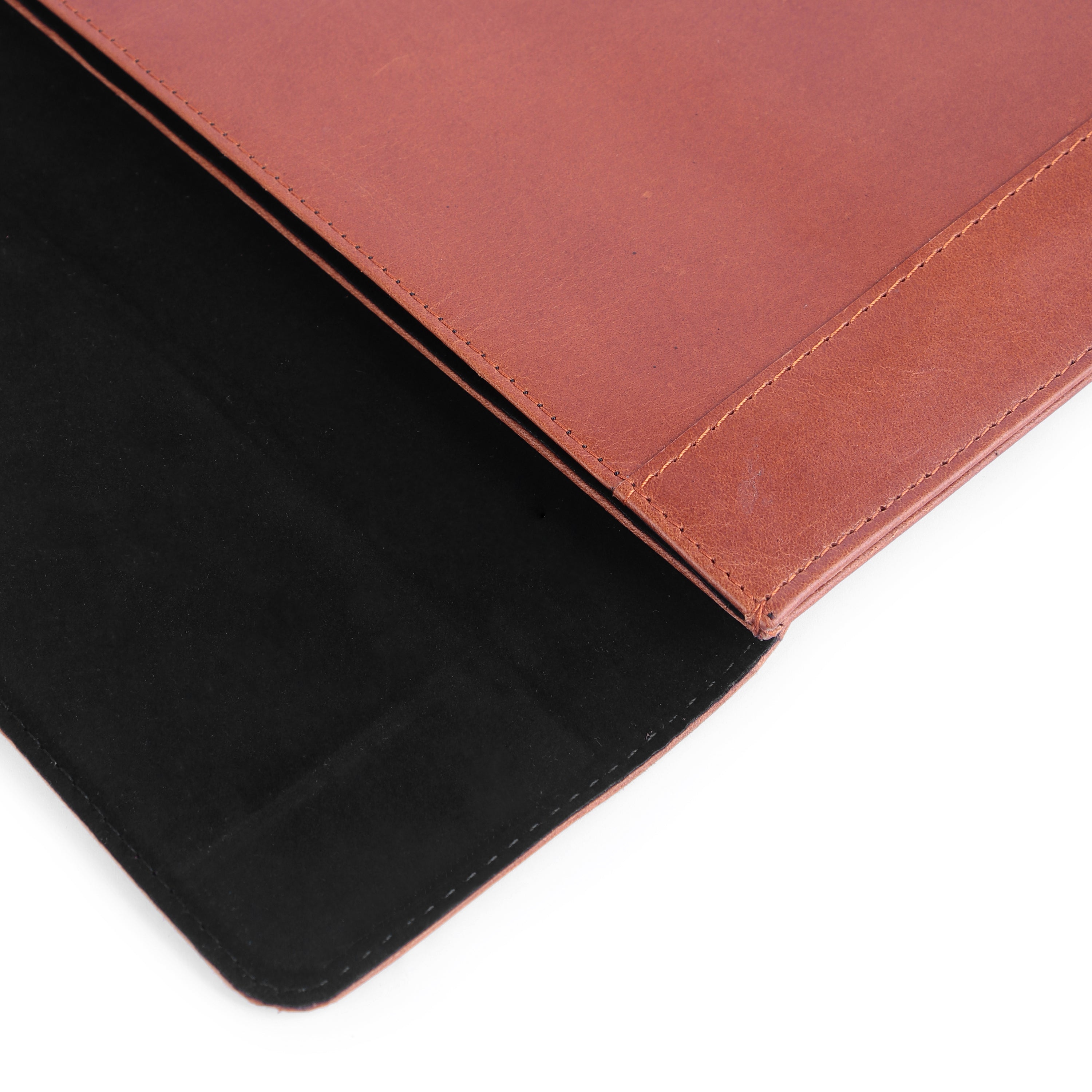 Close-up of a brown leather-bound book with a black interior on a white background