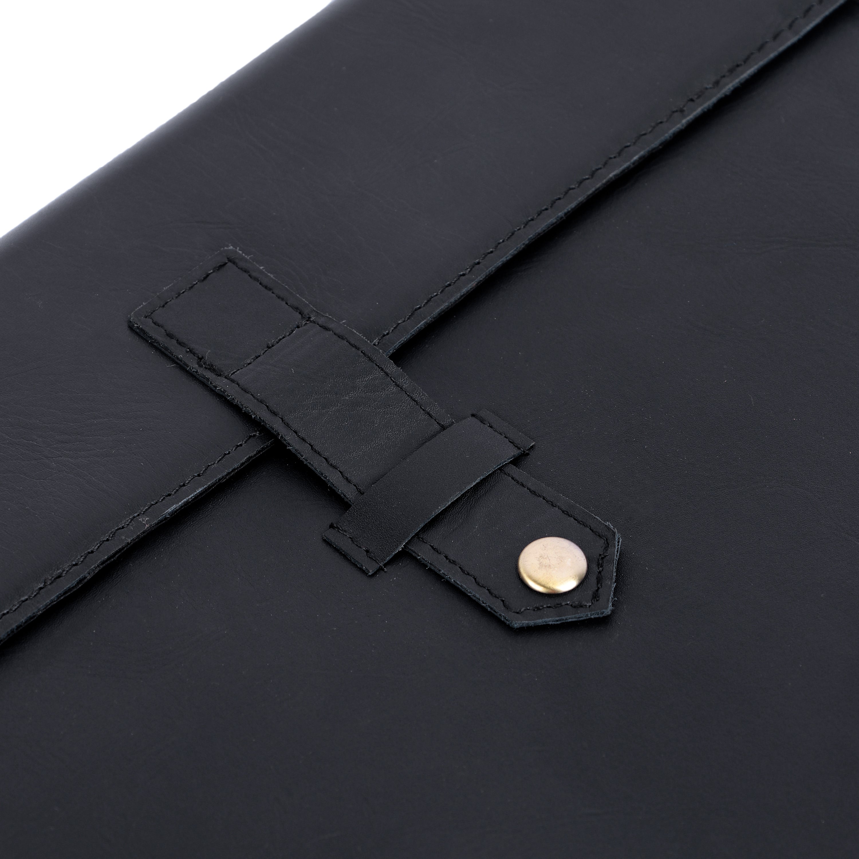 Close-up of a black leather bag with a strap and gold button on a white background