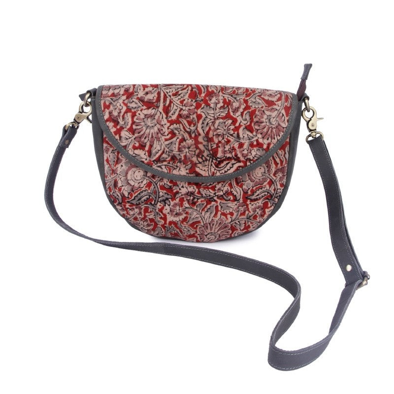 A floral sling bag with red and black colors, featuring a shoulder strap and a kalamkari fabric design.