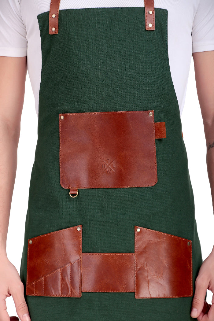 Green apron with brown leather pockets and straps on a white background