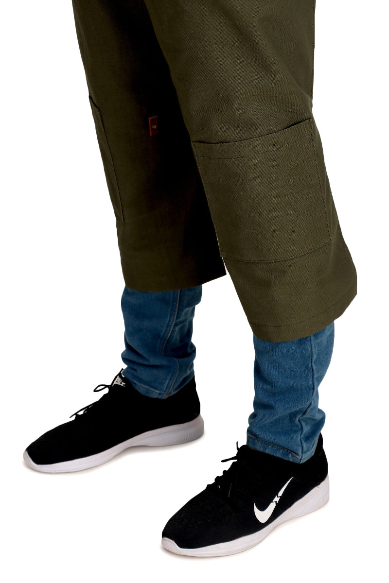Person wearing green cargo pants over blue jeans with black sneakers on a white background
