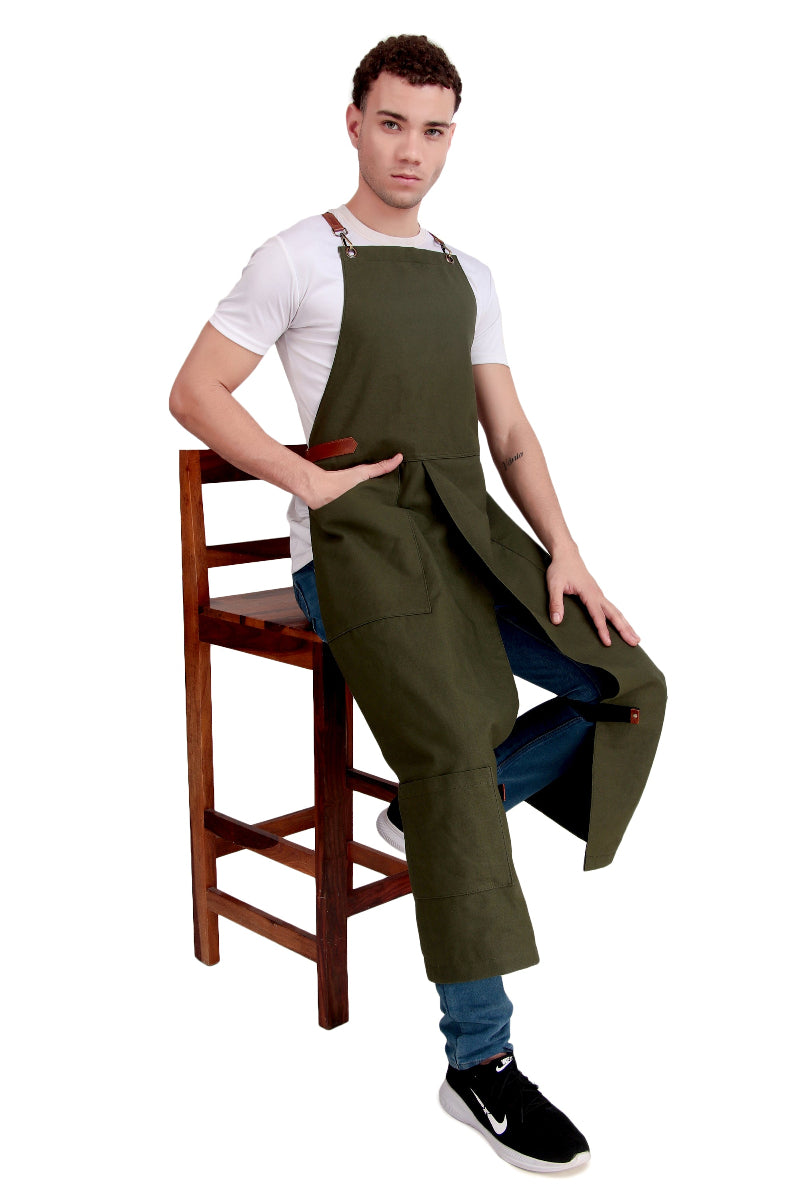 Man sitting on a chair wearing an olive green apron over a white shirt.