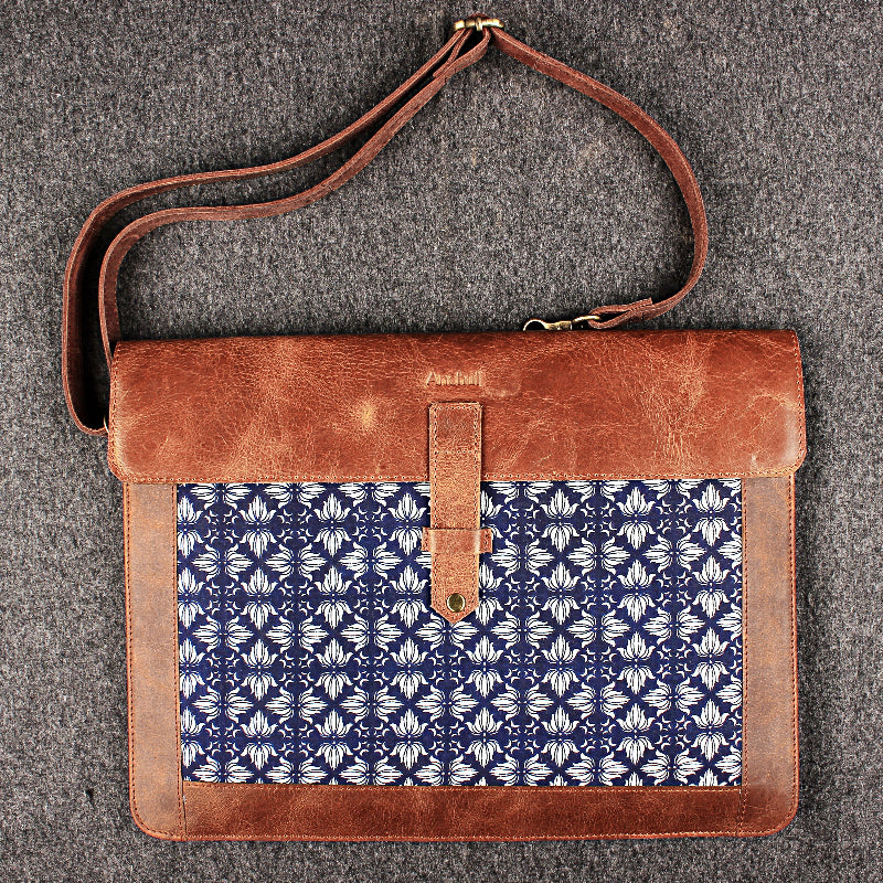 Brown leather bag with blue patterned flap on a gray background