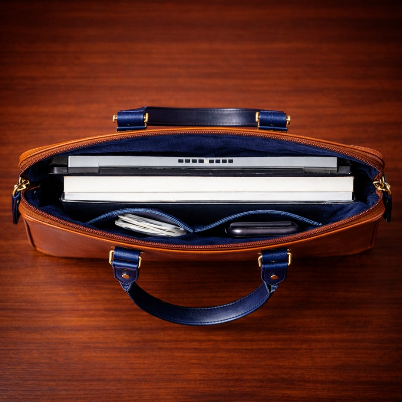 Brown leather briefcase with blue interior holding a laptop on a wooden surface