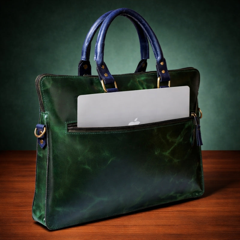 Green leather handbag with a laptop compartment on a wooden surface and green background