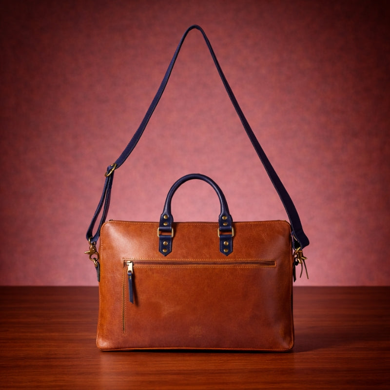 Brown leather handbag with a strap on a wooden surface and red background