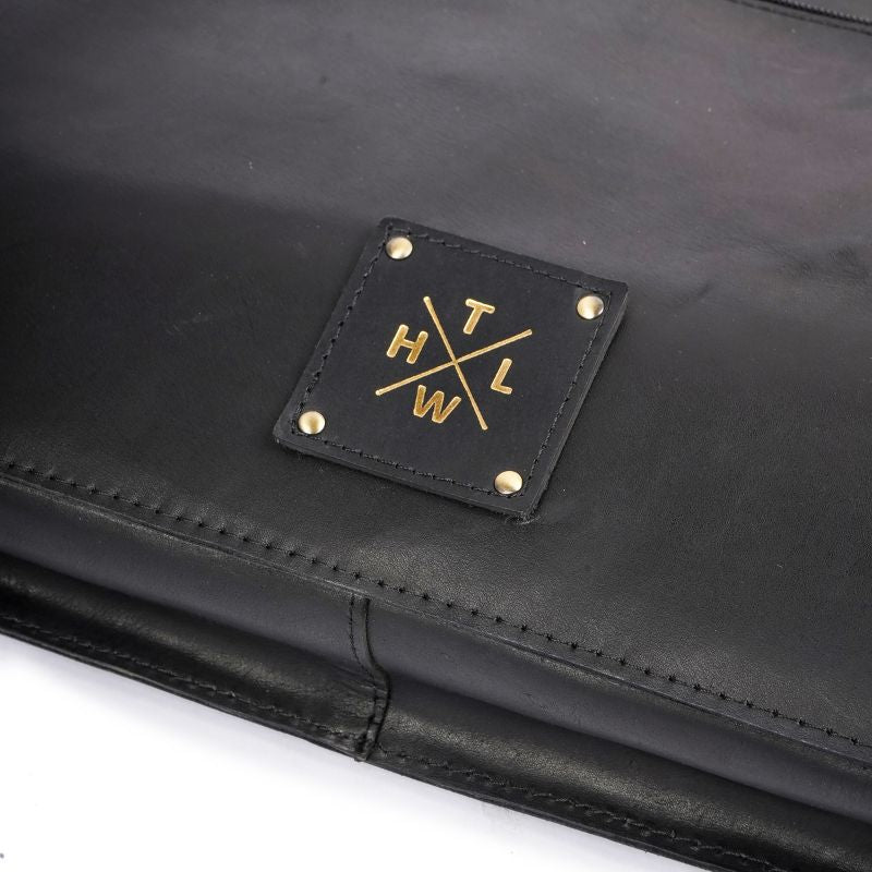 Black leather clutch with gold logo on a white background
