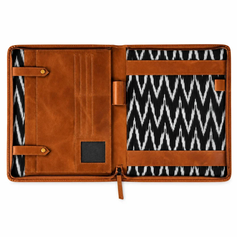 Open brown leather portfolio organizer with card slots, pen holders, document straps, and a black-and-white patterned interior.