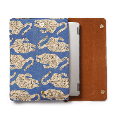 laprop sleeve with blue background and beige tiger pattern, next to a brown leather case