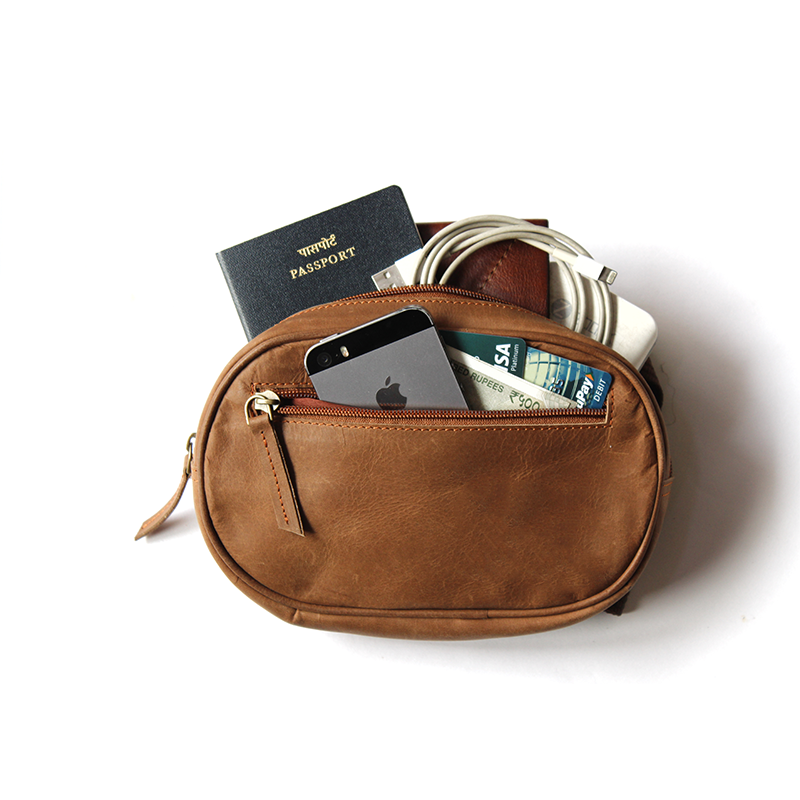 Brown leather pouch with items including a passport, phone, and money on a white background