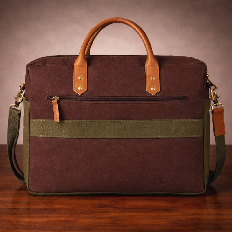 Brown and green bag with canvas & leather handles and straps on a wooden surface.