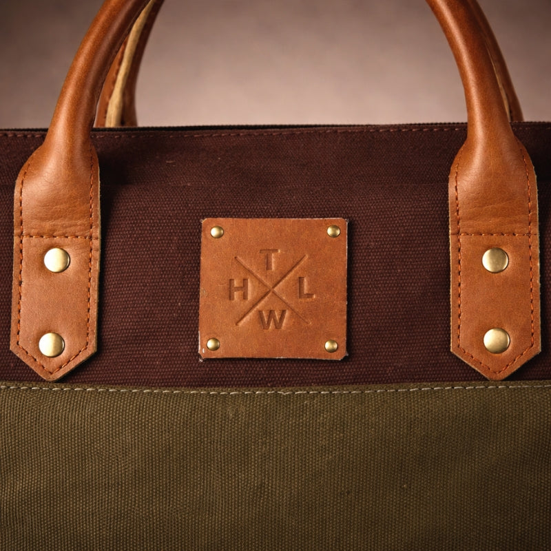 Brown leather bag with a leather patch featuring 'T L W H' on a brown background
