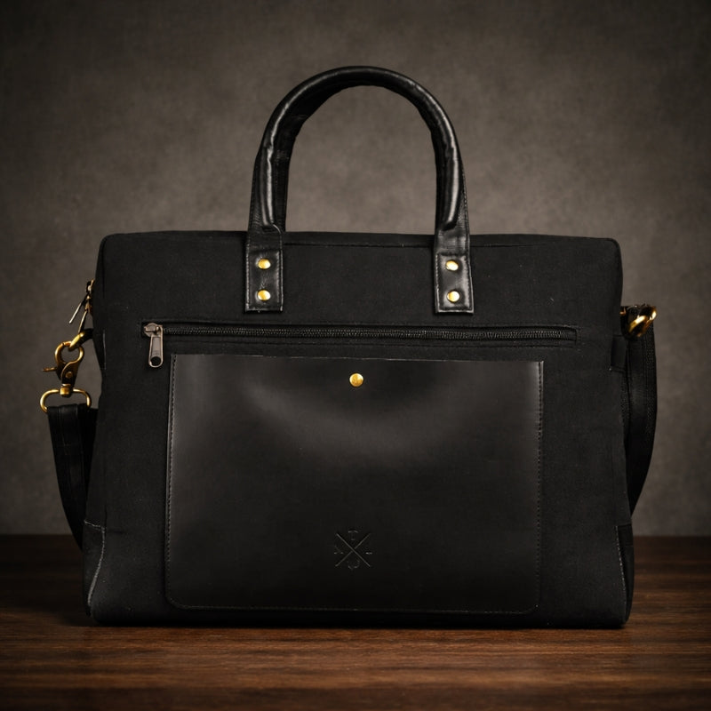 Black canvas & leather briefcase with gold accents on a wooden surface and dark background