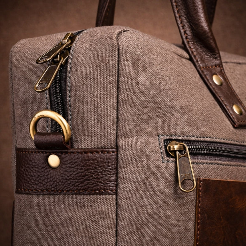 Close-up of a brown canvas leather bag with gold zippers and hardware.