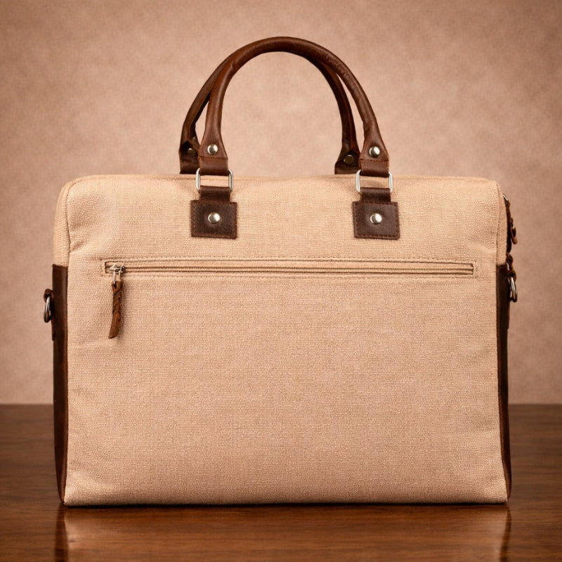 Beige canvas briefcase with brown leather handles and trim on a wooden surface.