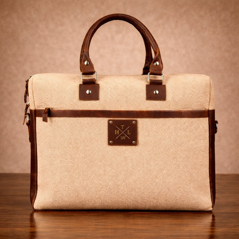 Beige canvas handbag with brown leather accents on a wooden surface and brown background