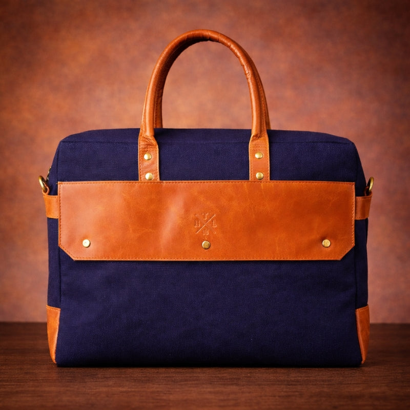 Navy blue bag with brown leather accents on a wooden surface and brown background