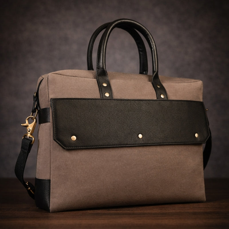 Brown canvas and black leather handbag with gold accents on a dark background