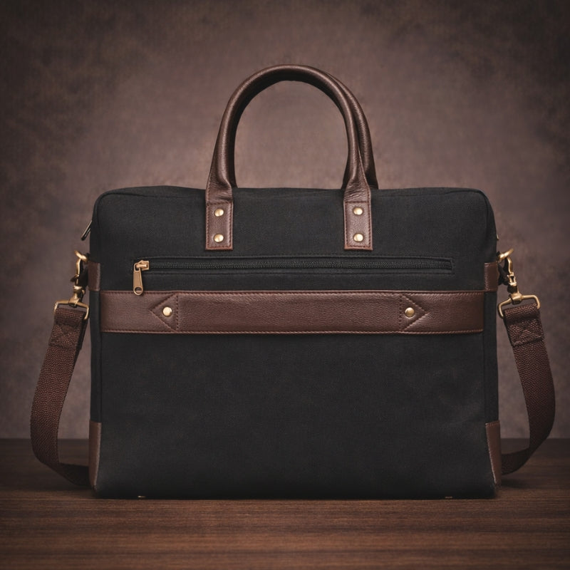 Black canvas & leather briefcase with brown accents on a wooden surface and dark background