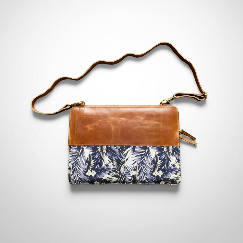 Crossbody bag with brown leather top section and floral patterned bottom section on a white background