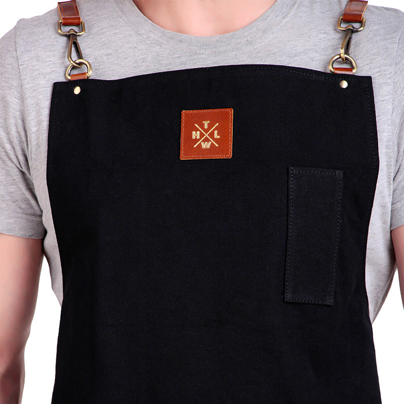 Black apron with a logo on a person wearing a gray shirt